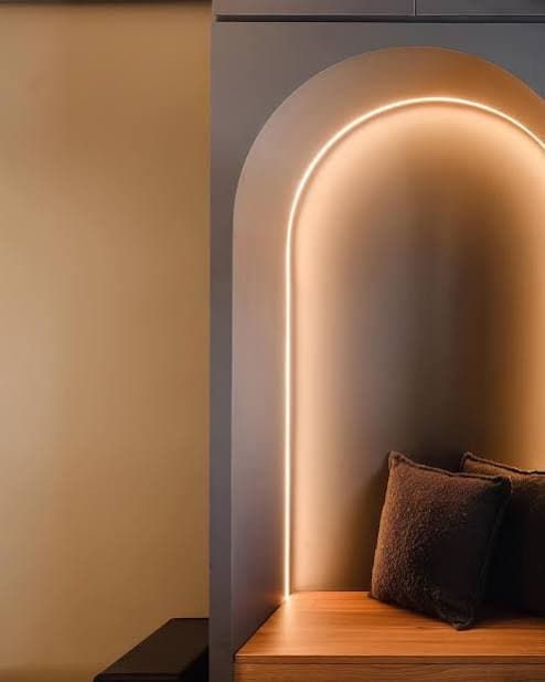 Arched decorative wall panels with lighting above upholstered banquette seating
